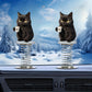 Pair of black cat coffee mug spring ornaments on a car dashboard above the air vents