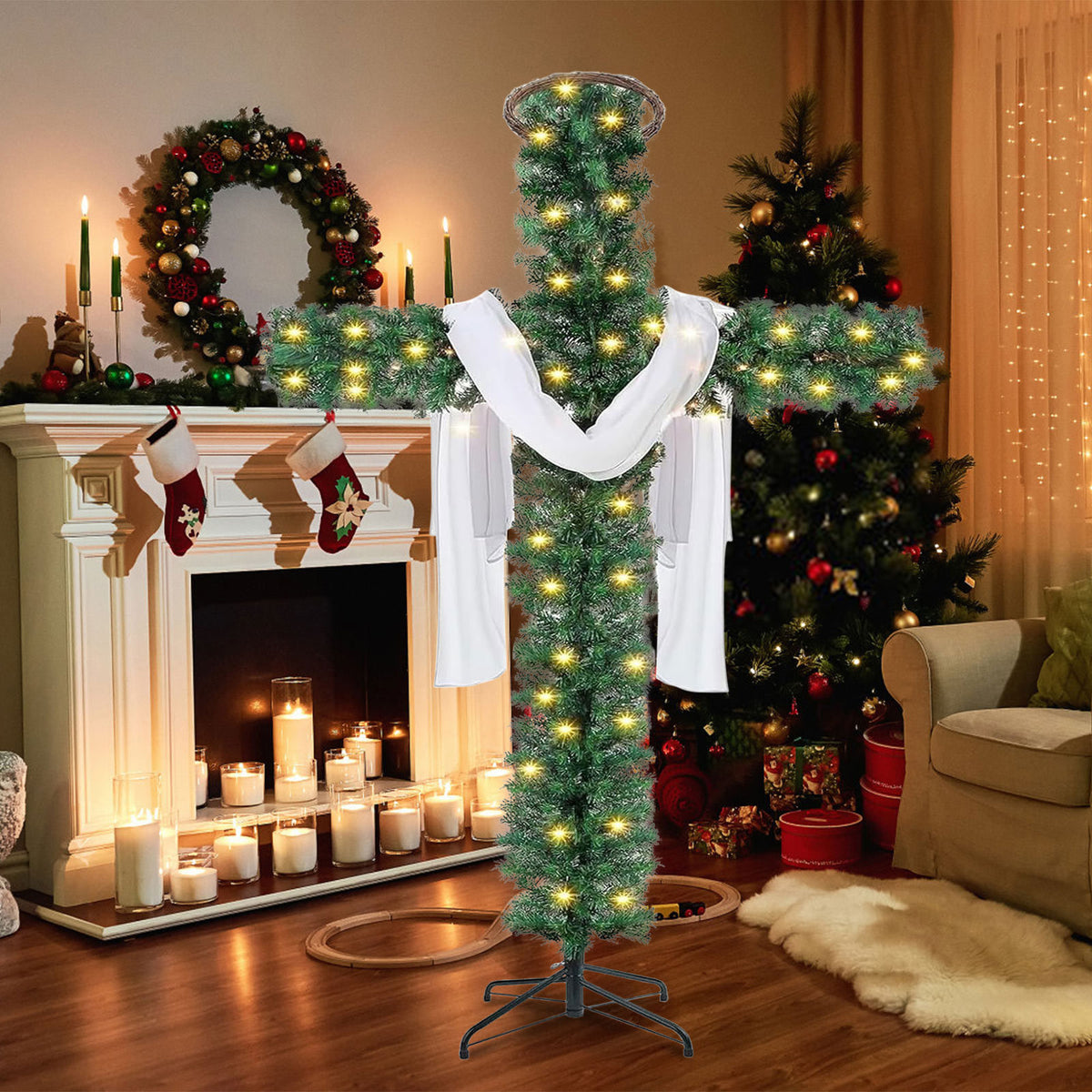 Green cross shaped Christmas tree with warm white lights and a white cloth beside a fireplace with stockings