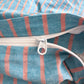 Zipper opening on a blue and coral striped cotton quilt cover, close up of the white zip and pull