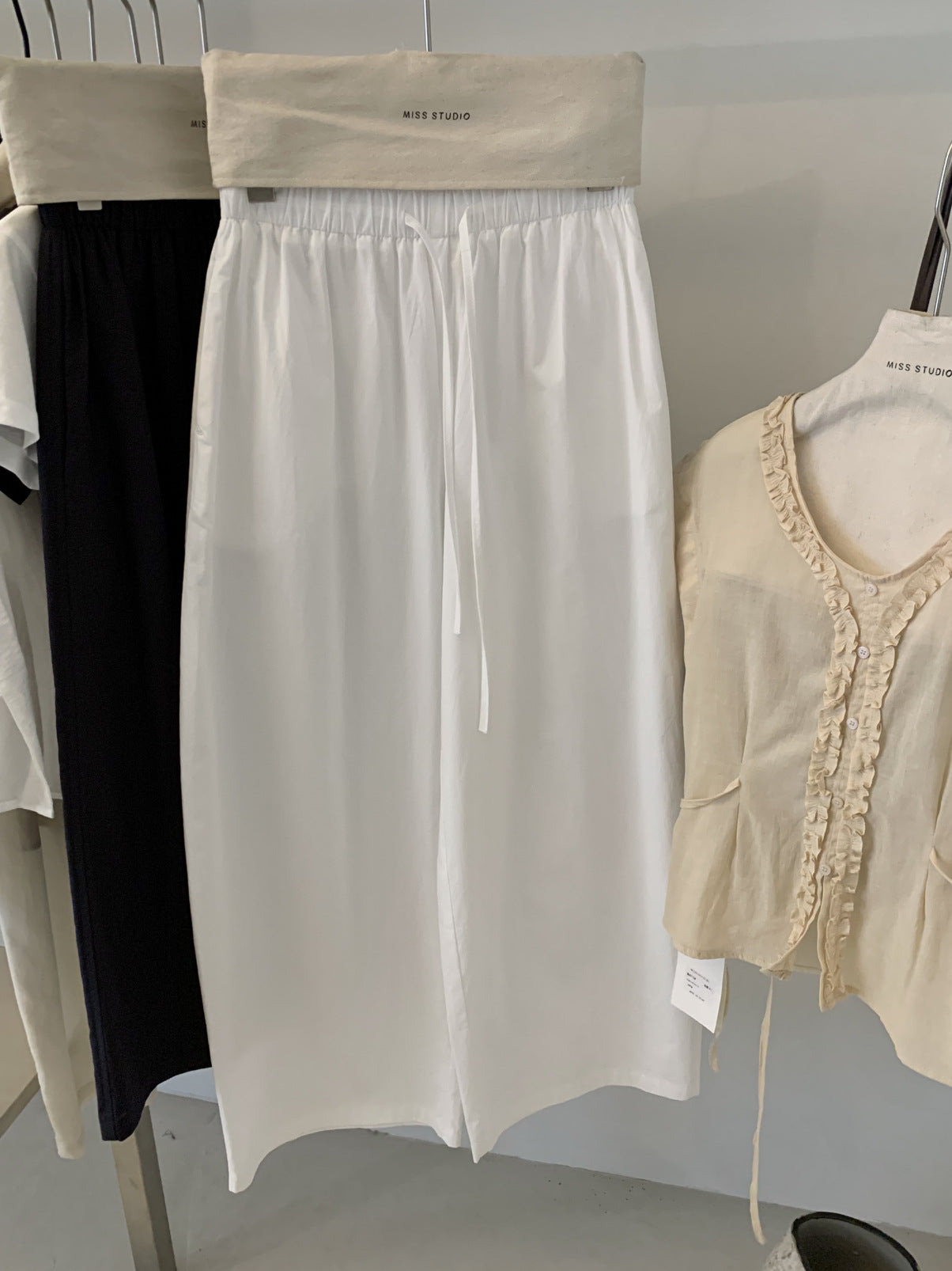 White cotton barrel leg trousers hung with elastic drawstring waist detail