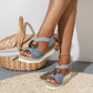 Dusty blue snakeskin wedge sandal with metal ring beside a wicker basket on a woven mat