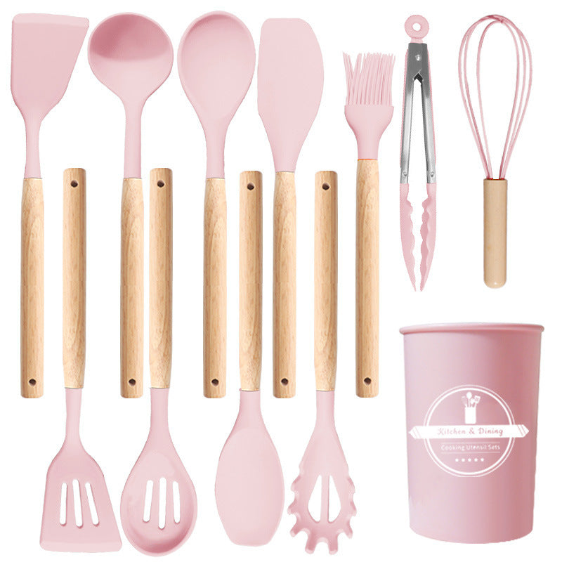 Pink silicone utensil set laid out flat with turners, spoons, ladle, spaghetti server, brush, tongs, whisk and holder
