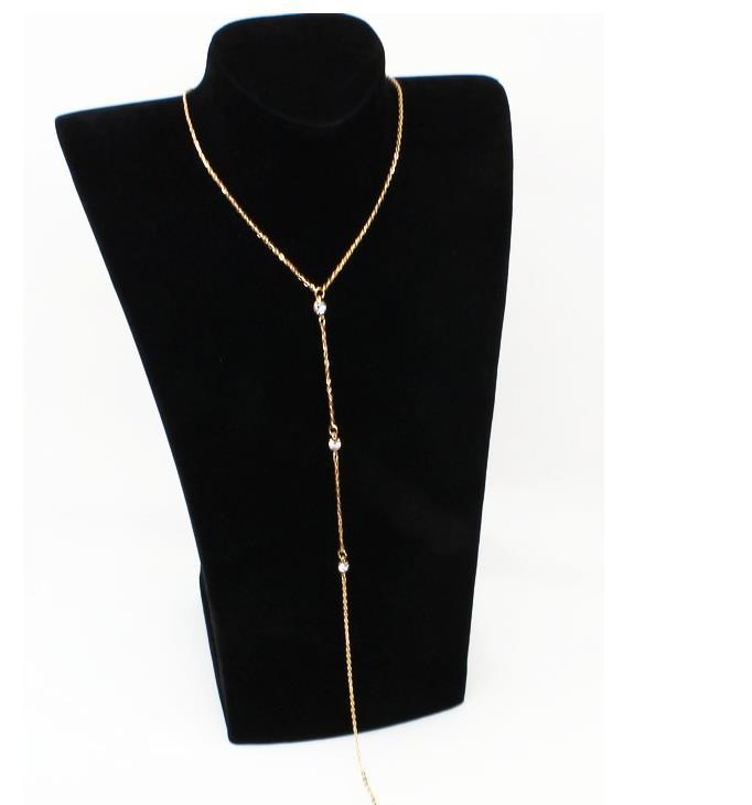 Full length gold tone rhinestone lariat necklace shown hanging on a black display bust
