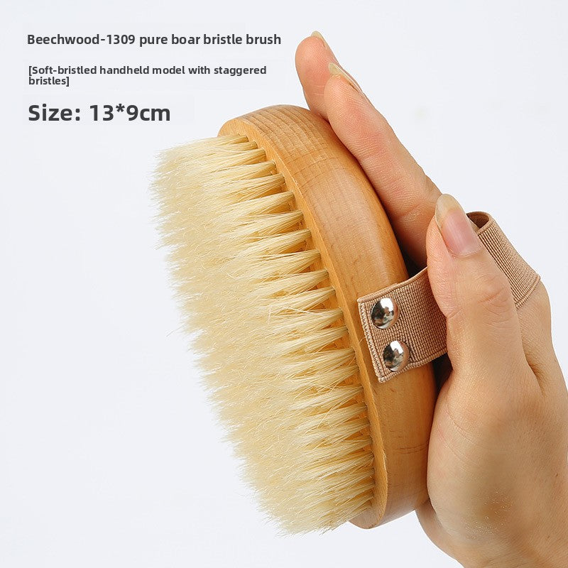 Hand holding the Beech 1309 pure boar bristle body brush, soft bristled model with staggered bristles, 13 by 9 cm