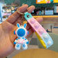 Single blue helmet astronaut rabbit charm on a pink and yellow silicone pop strap held in a hand