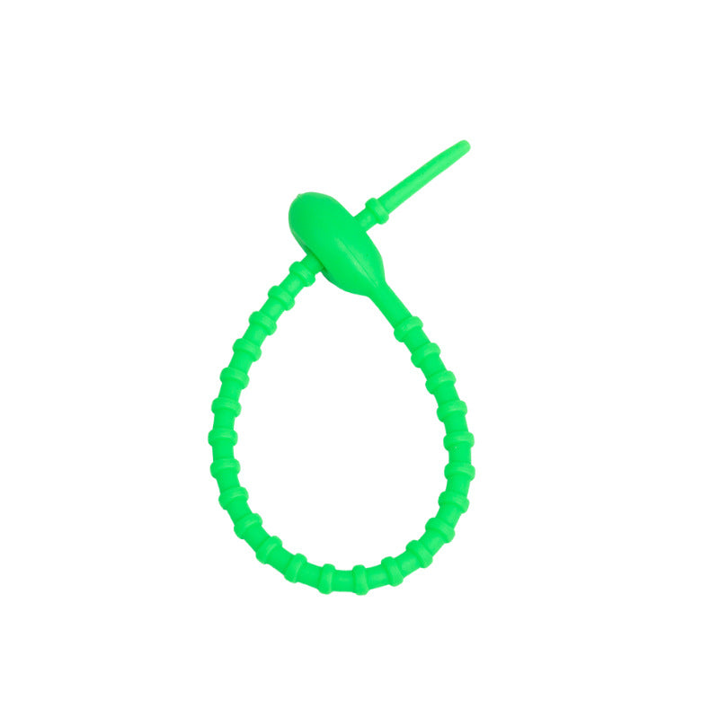 Soft silicone tadpole cable tie coiled into a loop to show the reusable cinch closure