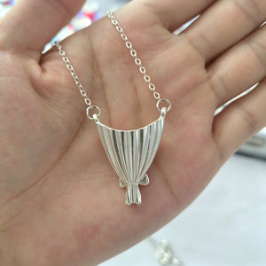 Silver tone bouquet pendant seen from the pleated reverse, fine flutes fanning out from the bow