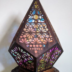 Faceted boho table lamp with pierced floral shade glowing multicolor in a dim room