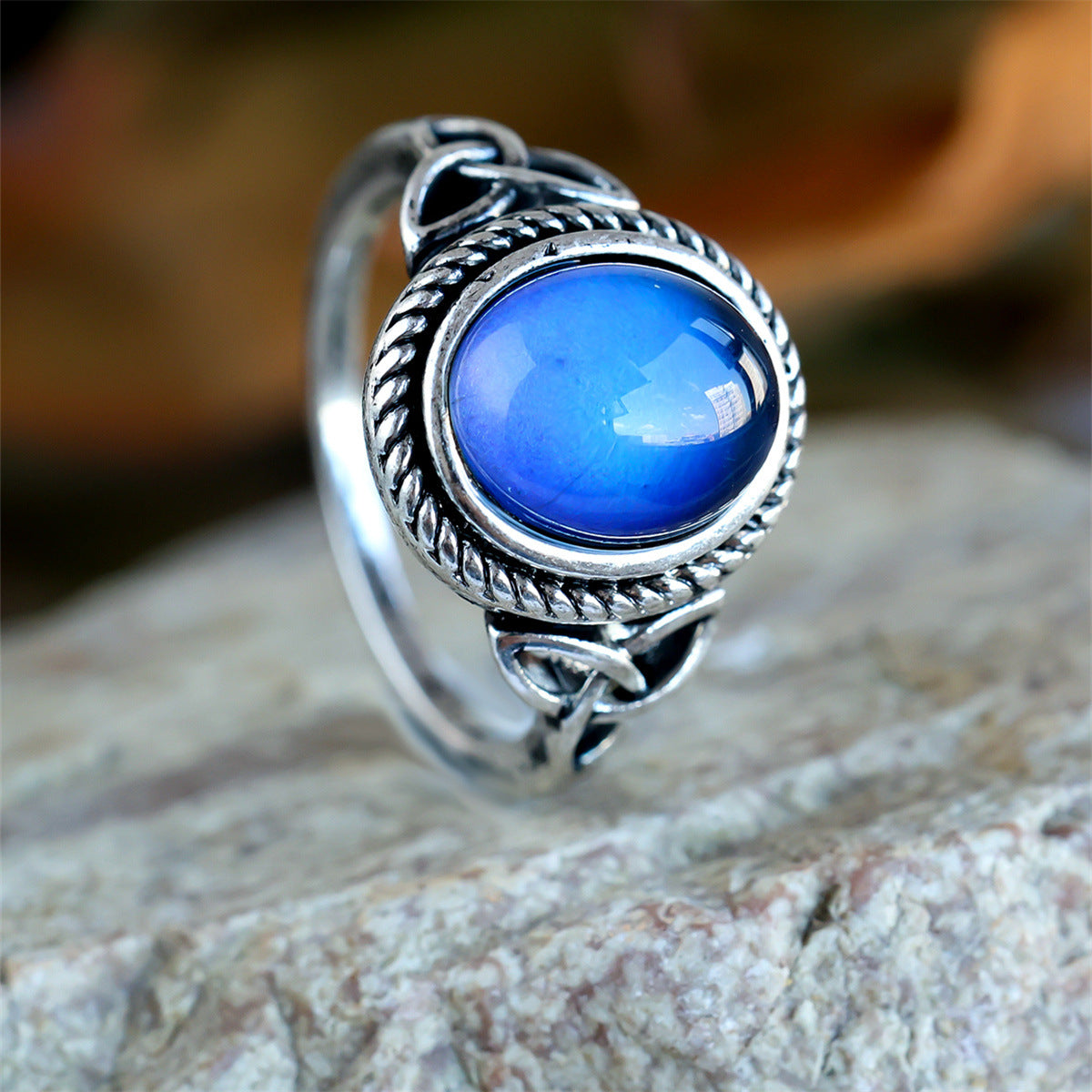 Close up of glossy oval cabochon shifting blue and green in twisted rope bezel