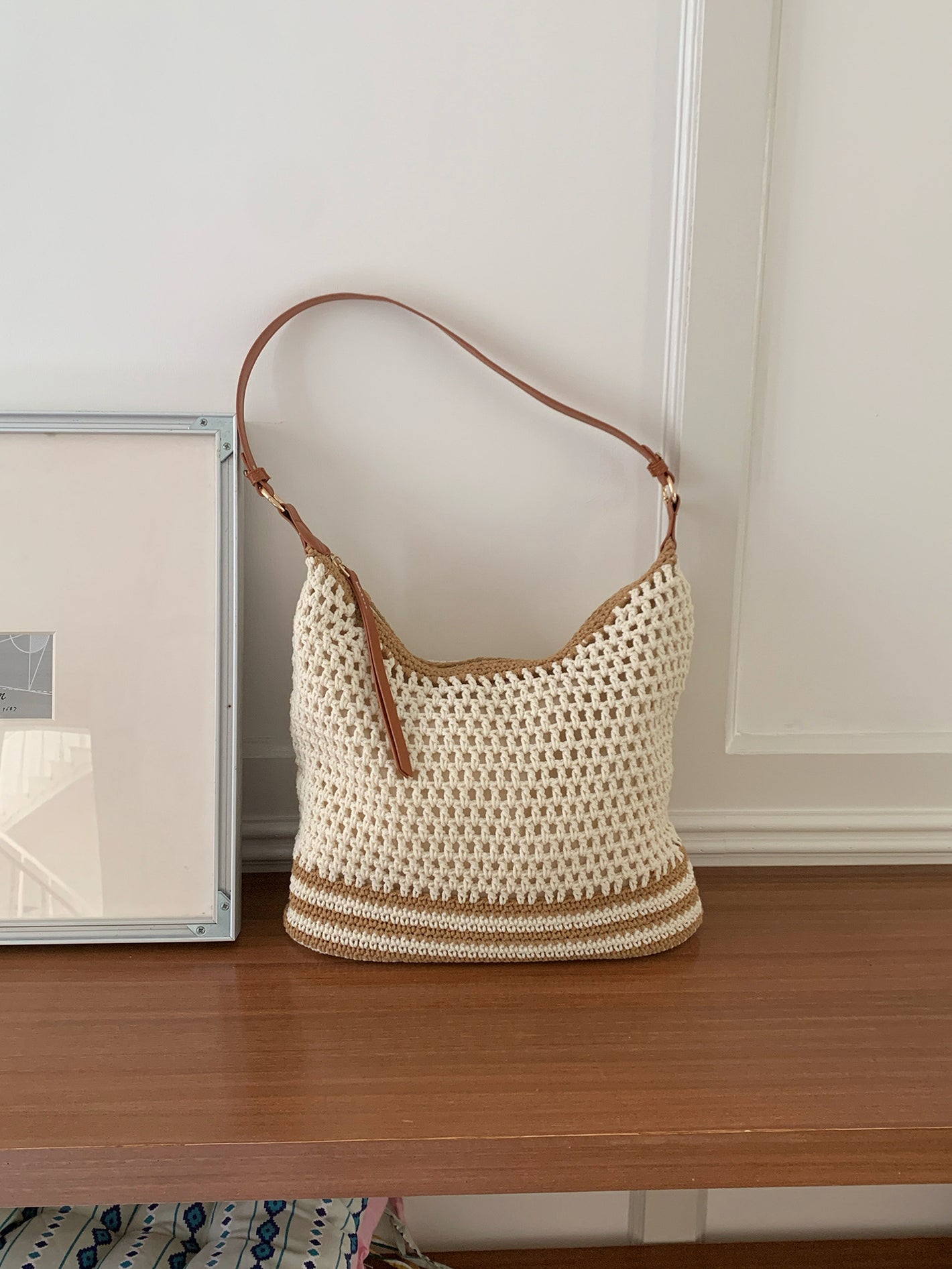 Cream open weave shoulder bag with tan stripes and an adjustable brown strap