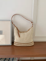 Cream open weave shoulder bag with tan stripes and an adjustable brown strap