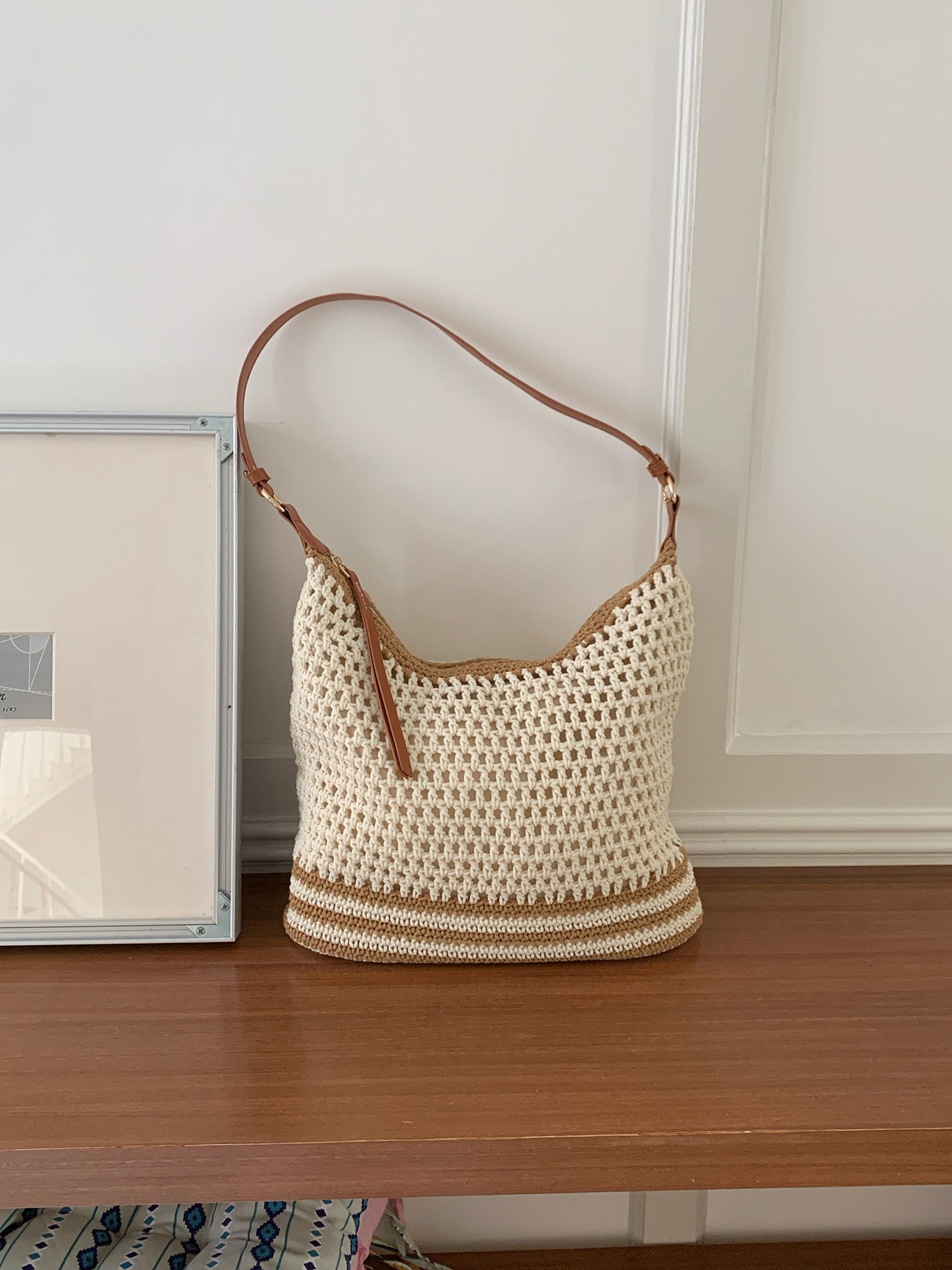 Cream open weave shoulder bag with tan stripes and an adjustable brown strap