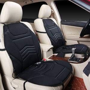 Black heated seat cushions fitted on the beige front seats of a car with cords running down to the plug
