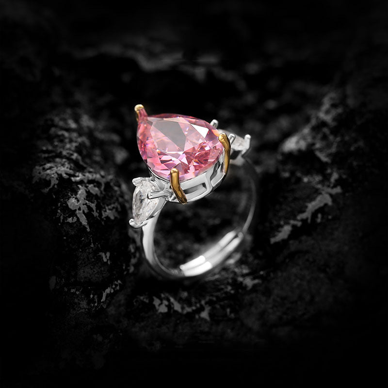 Pear cut pink simulated diamond held in gold toned prongs above a silver toned adjustable band