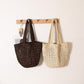 Brown and beige open weave paper straw shoulder bags hanging side by side on a peg rack