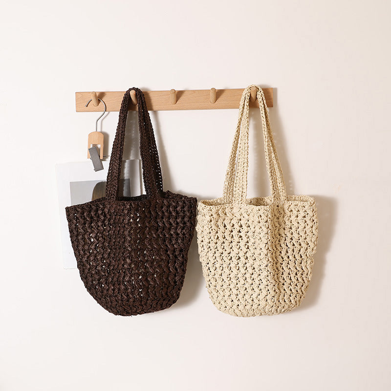 Brown and beige open weave paper straw shoulder bags hanging side by side on a peg rack