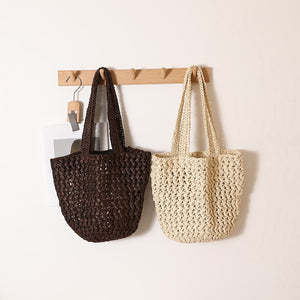 Brown and beige open weave paper straw shoulder bags hanging side by side on a peg rack