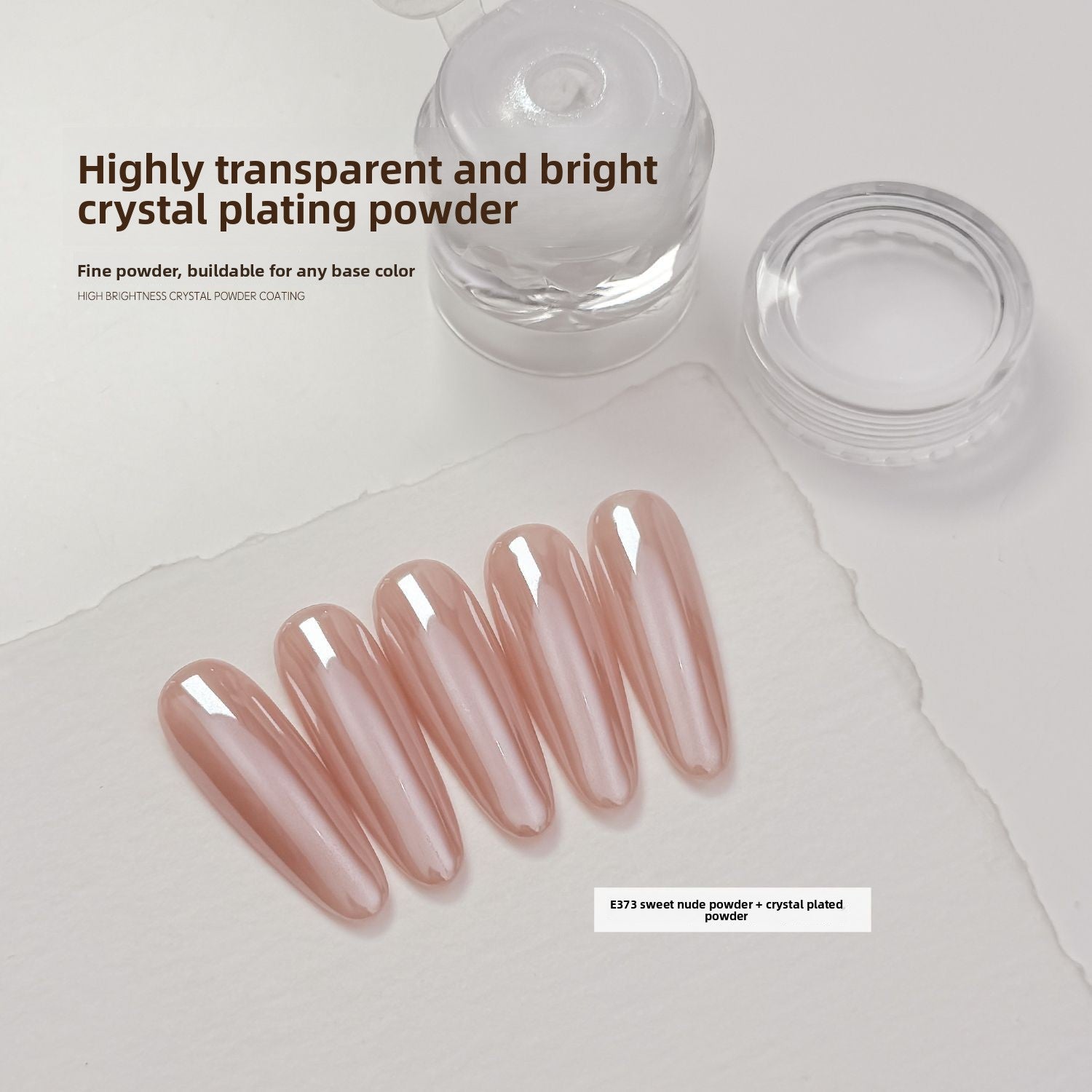 Long glossy nude press-on nails beside a small clear jar of crystal coating powder