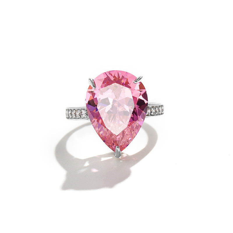 Large pear cut pink simulated diamond with clear pave running down both shoulders of the band
