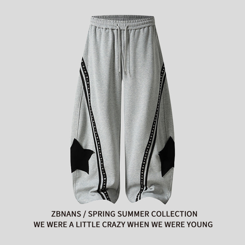 Star patch drawstring pants in black, front view showing waist tie and legs