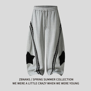 Star patch drawstring pants in black, front view showing waist tie and legs