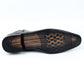 Underside of a black ankle boot showing the black plastic sole and a perforated textured insole pattern