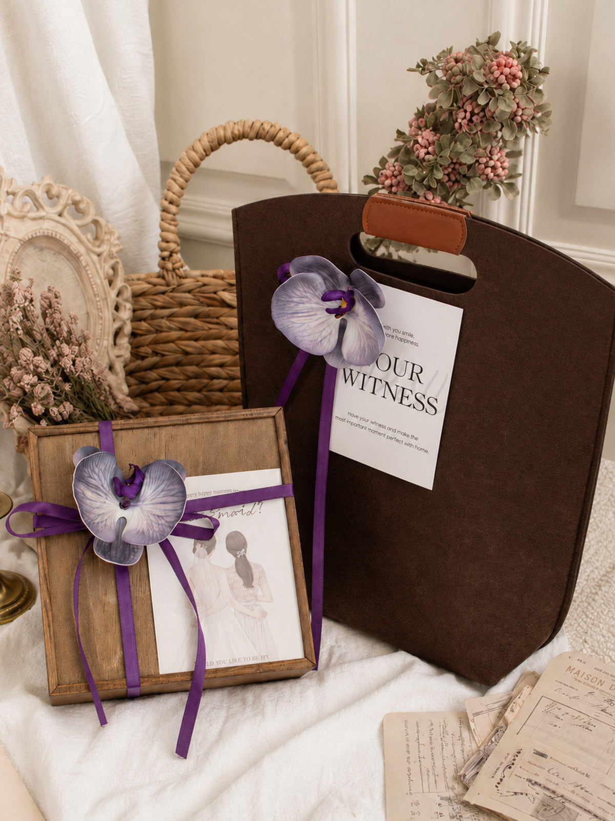 Monet Purple option, wooden gift box with a purple ribbon, orchid flower and card beside a brown bag with a cut-out handle