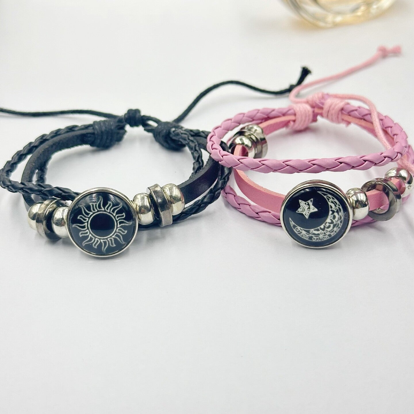 Black braided cord bracelet with a sun charm worn on a model wrist