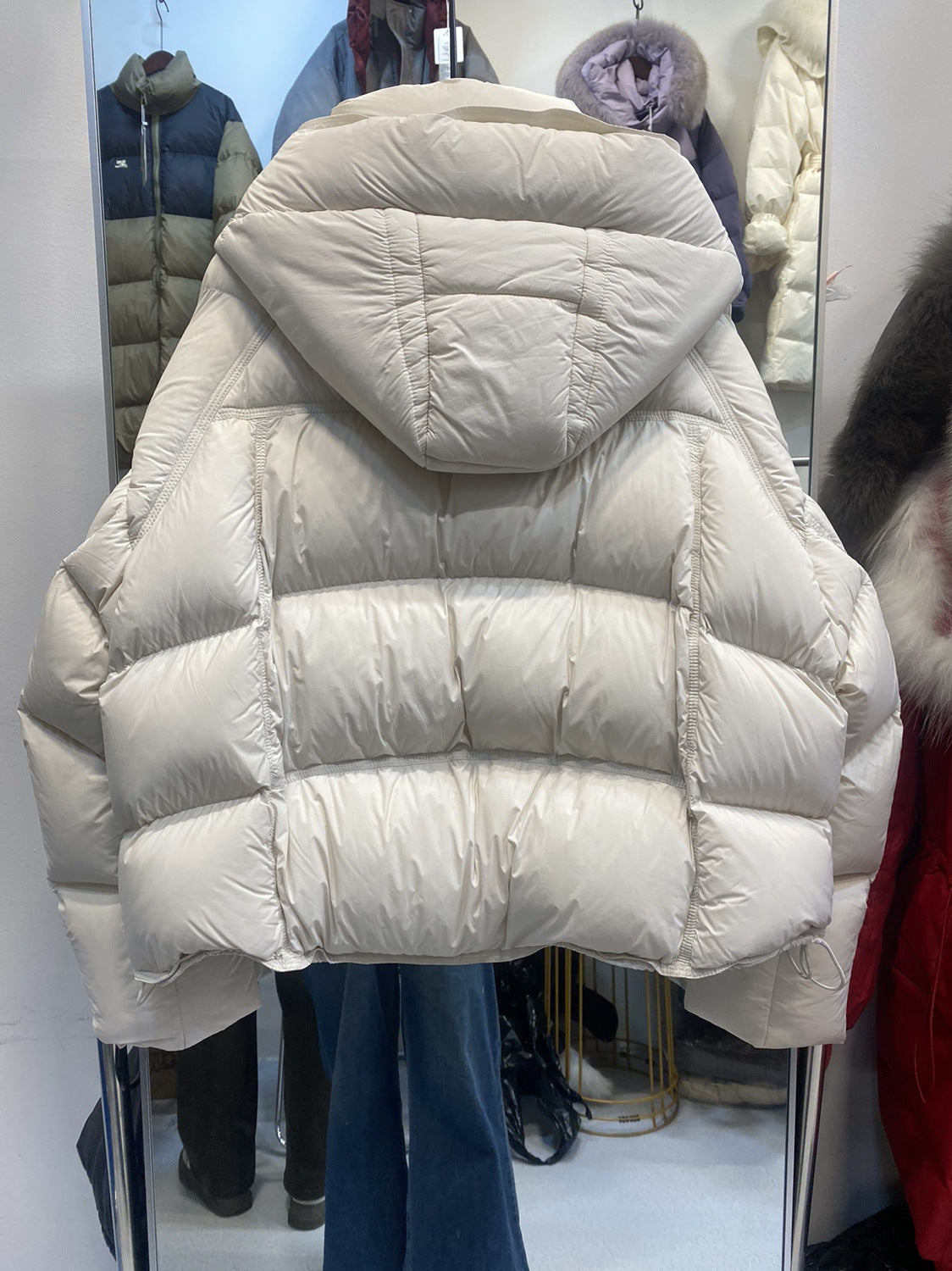 Down puffer jacket laid out to show the quilted sleeves and short hem near the hip