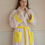 Woman in a pink and white striped cotton terry bathrobe with yellow trim and a shawl collar