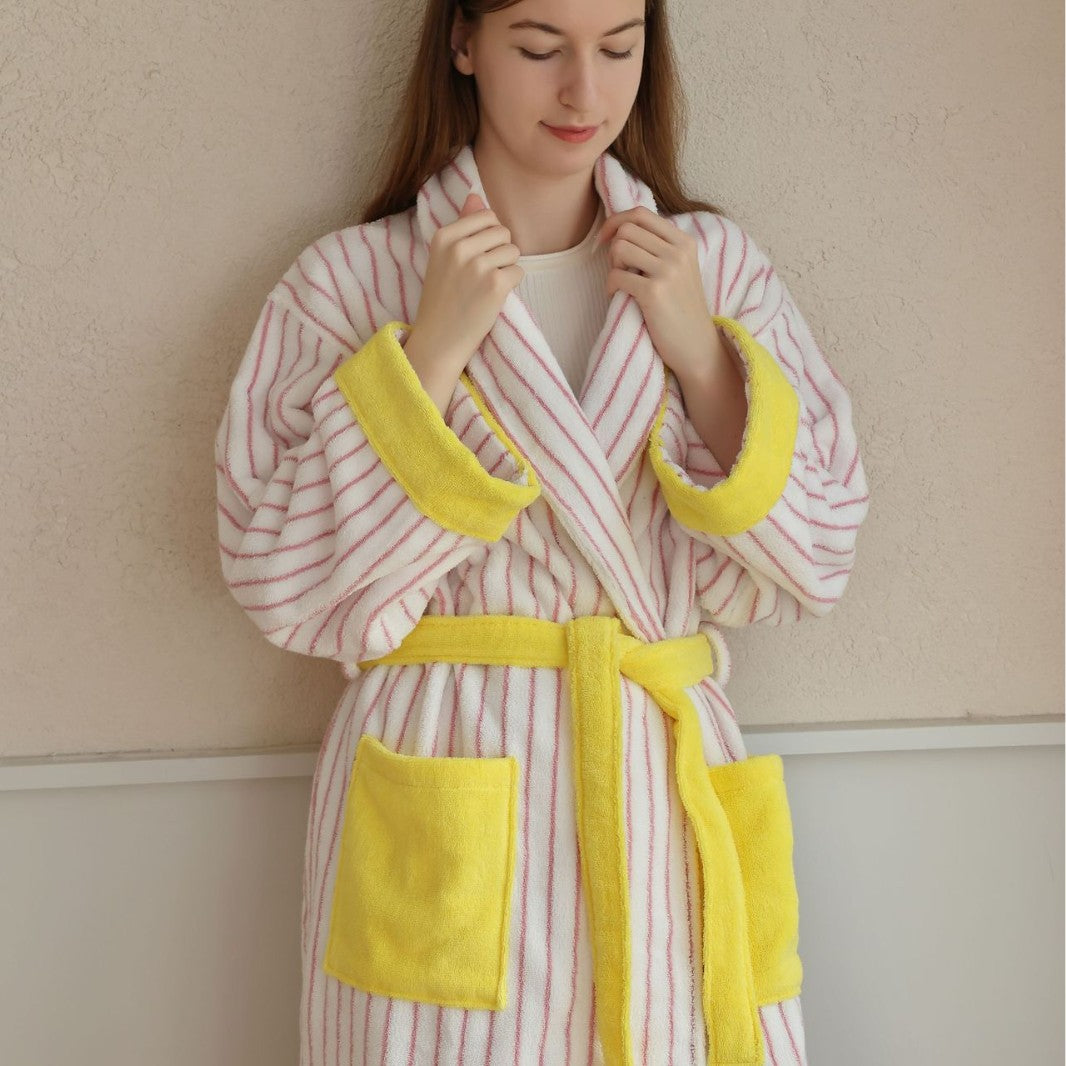 Woman in a pink and white striped cotton terry bathrobe with yellow trim and a shawl collar