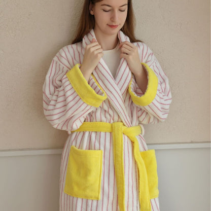 Woman in a pink and white striped cotton terry bathrobe with yellow trim and a shawl collar