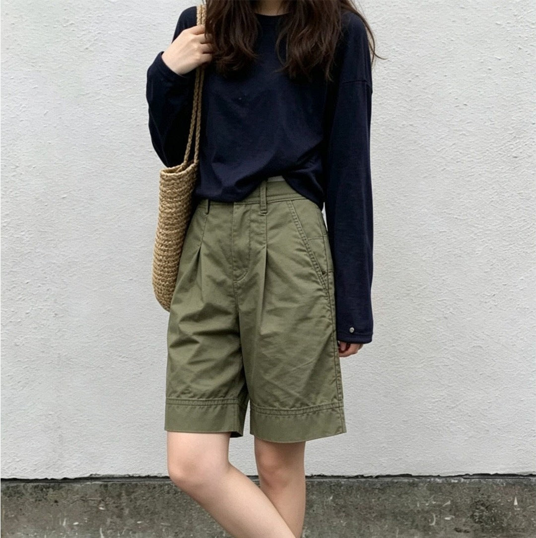 Front view of olive green pleated Bermuda shorts with high waist and knee-length cuffed hem