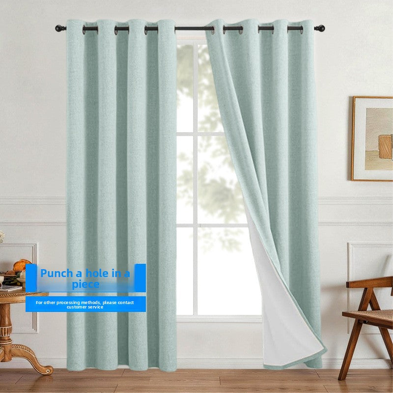 Linen look polyester blackout grommet curtain panel with white thermal backing drawn across a sunlit room frame