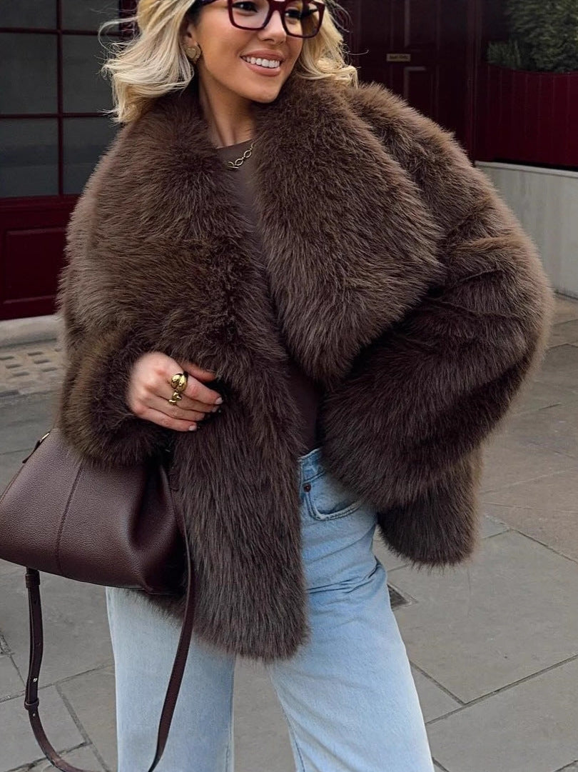 Woman in a dark brown vegan fur jacket with glasses and a brown bag, in light blue jeans on a street