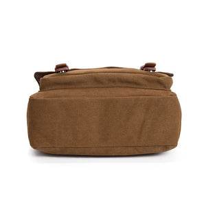 Base of the brown canvas messenger bag, flat bottom panel and the leather flap straps seen from below