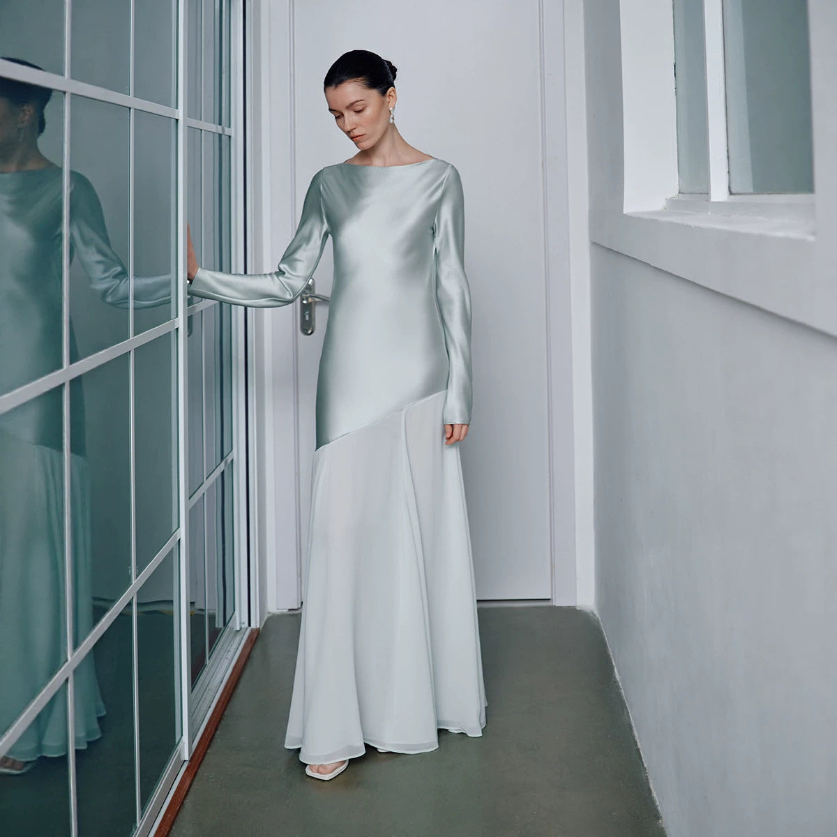 Side profile of the satin gown showing the long sleeve and fishtail flare