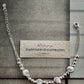 Silver bracelet laid open beside a card, showing clasp, extender chain and brushed beads