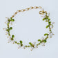 Peach and orange glossy berry beads with green leaves on a gold tone chain bracelet