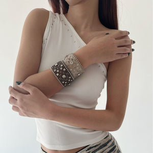 Model wearing a wide rhinestone leather cuff bracelet high on the forearm