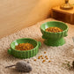 Kibble in a green ceramic raised bowl and a low bowl on a shaggy rug, a styled scene not among the listed designs