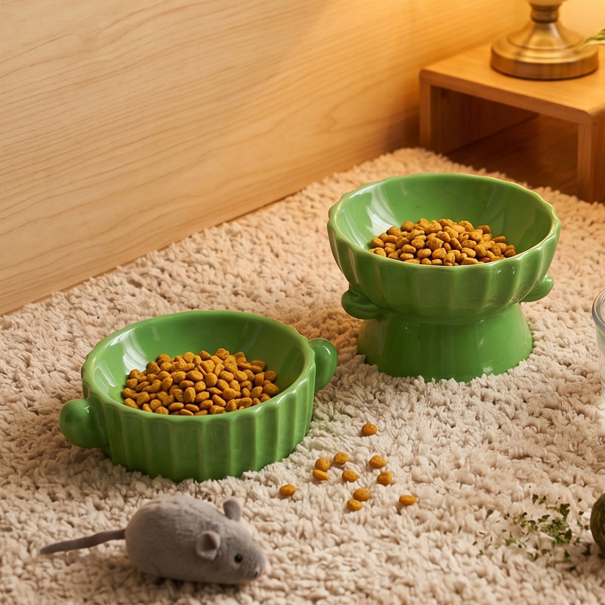 Kibble in a green ceramic raised bowl and a low bowl on a shaggy rug, a styled scene not among the listed designs