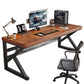 Walnut top desk with a black K-shaped frame on a white background with a monitor and a gray chair