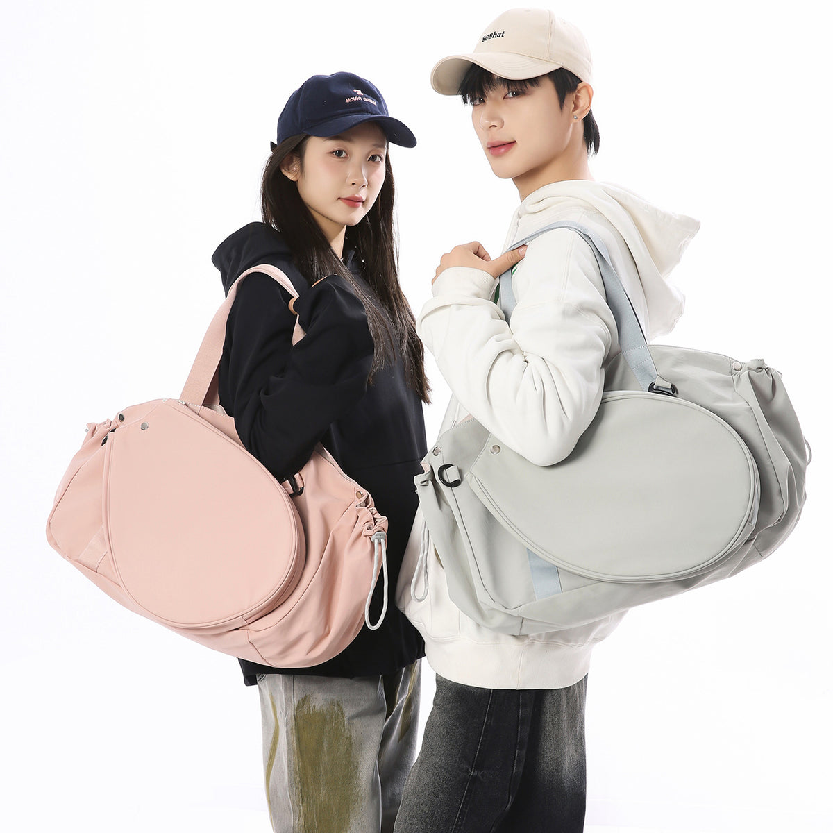 Man and woman carrying pink and mint green racket-front sports bags on a white background