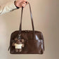 Side angle of the Retro Pillow Shoulder Bag showing the strap and rounded brown body
