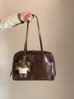 Side angle of the Retro Pillow Shoulder Bag showing the strap and rounded brown body