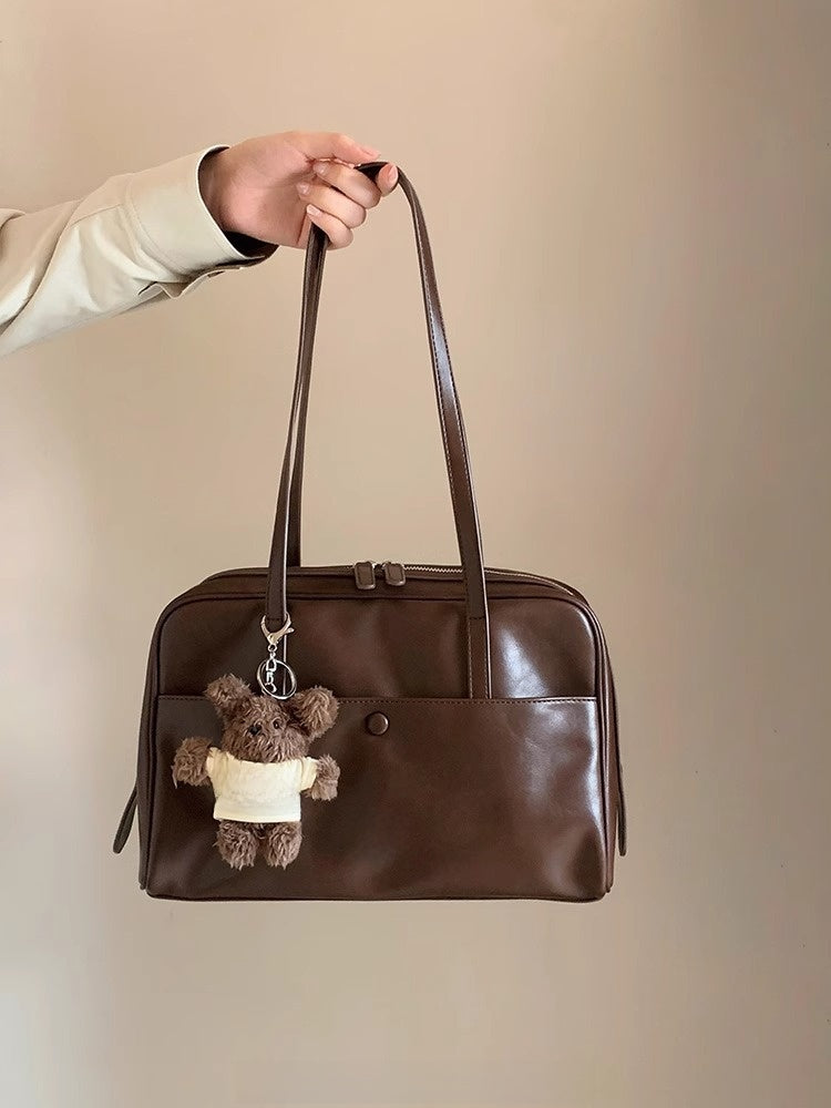 Side angle of the Retro Pillow Shoulder Bag showing the strap and rounded brown body