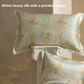 Silk pillowcase printed with pastel wildflowers on a beige ground, shown with a second case on a stone pedestal