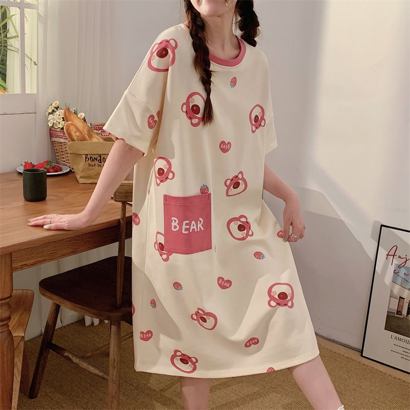 Woman at a table in a cream short sleeve nightgown with a pink collar, pink bear prints and a BEAR pocket, view 1 of 2
