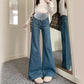 Medium blue flared maternity jeans with a gray stretch belly panel, worn with a white crop top next to a mirror